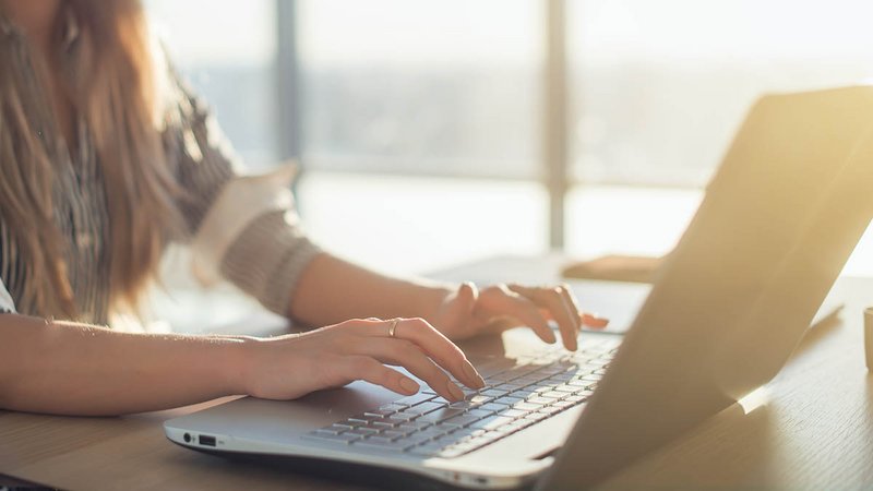Frau tippt am Laptop