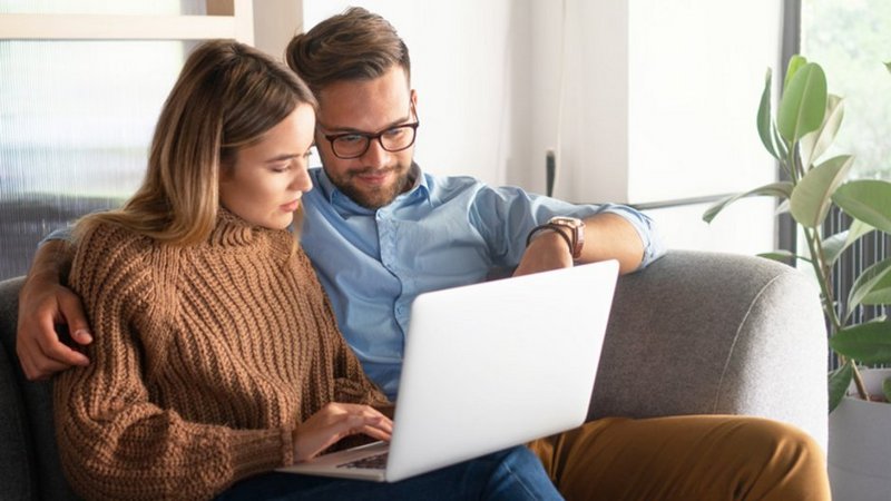Ein Paar sitzt auf dem Sofa und schaut in einen Laptop