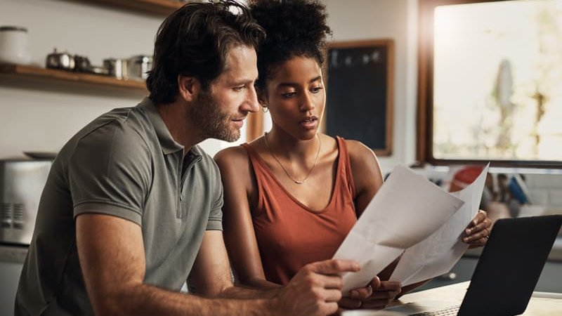 Ein Paar sitzt mit Unterlagen vor dem Laptop